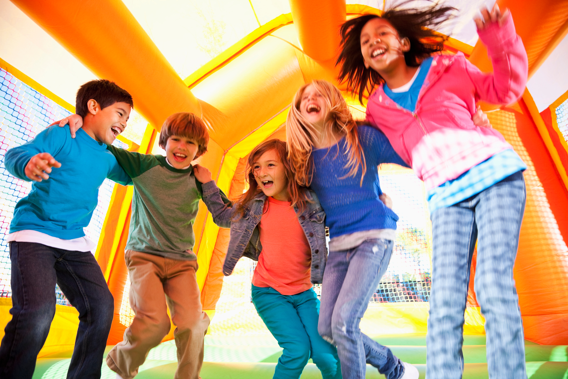 Children playing on bounce houses at a backyard birthday party